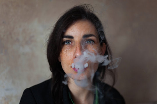 Portrait of a young woman blowing a cigarette smoke