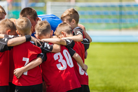 Children sports soccer team. Kids standing together on the football pitch. Soccer coach motivational team talk. Youth football soccer coach motivating players before match. © matimix