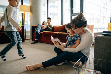 Young mom teaching little girl to read inside
