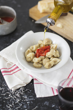 Pourng olive oil on homemade gnocchi dish and tomato sauce