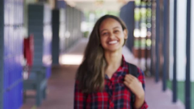 Black teenage girl walks into focus in high school corridor