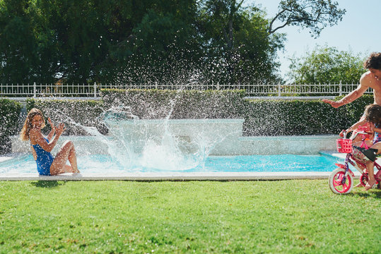 Boy diving in to pool splashing the family having fun