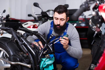 bearded man worker working at restoring motorbike in workshop