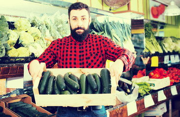 Shop assistant demonstrating zucchinis
