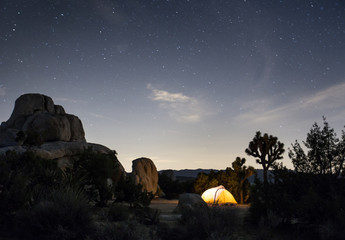 Camping tent illuminated at night under bright starry sky