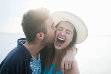 A young couple laughing and kissing while on vacation