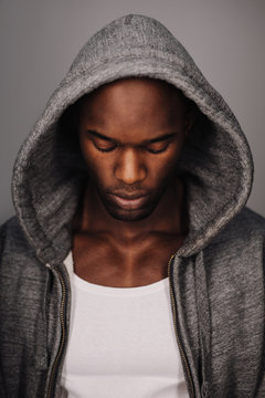 Young African man in hoodie looking down