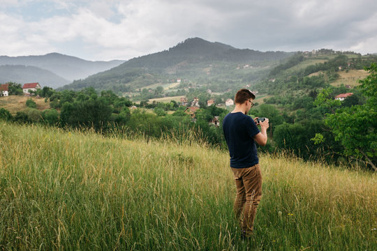 young male on valley hillside taking picture of the photographic landscape