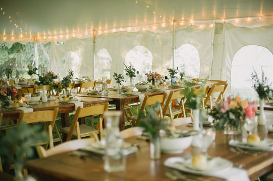 Botanical greenery wedding table setting in tent with string lights