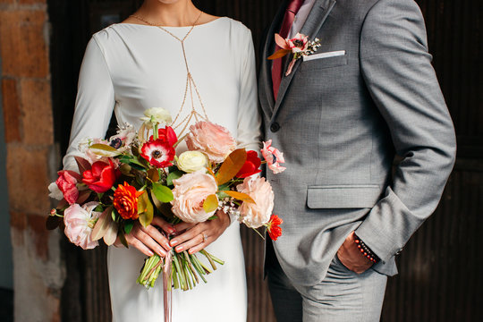 Upclose of man in a suit and a woman holding a floral bouquet