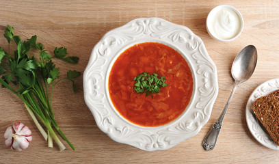soup in a bowl with dill, sour cream and black bread on wooden background