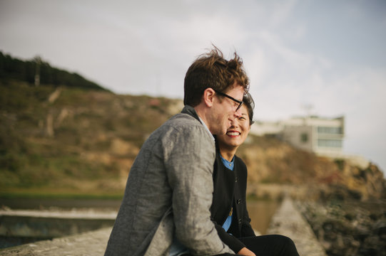 Happy and smiling interracial engaged couple at sutro baths at sunset in san francisco california