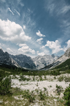 sparse valley surrounded by a rugged mountain range with dramatic sky