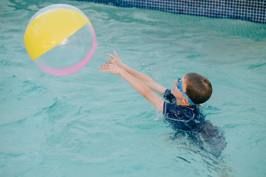 Child launching ball into air in swimming pool