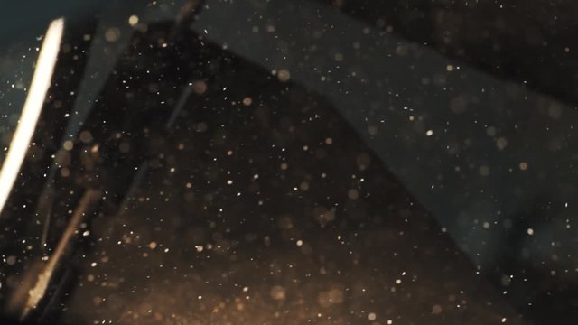 Lots beautiful specks of dust flying around in workshop warm light, abstrakt background slowmotion