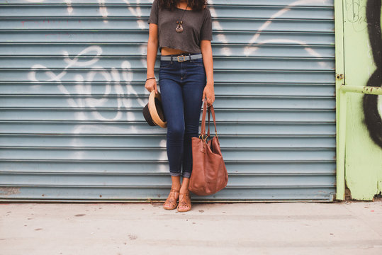 Stylish woman holding chic bag and hat
