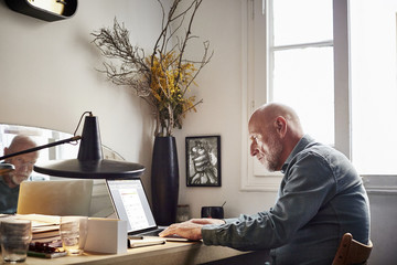 Confident Senior Businessman Using Laptop At Home