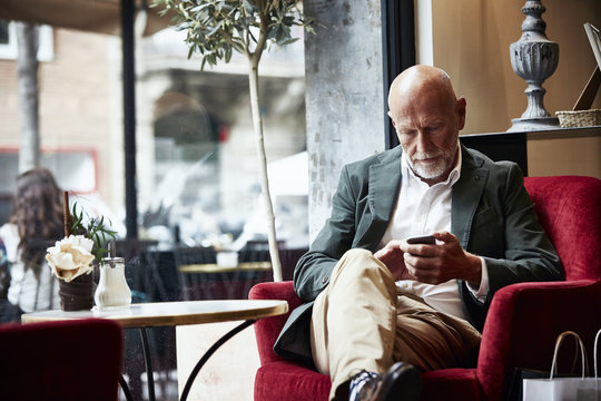 Senior Man Using Mobile Phone In Restaurant