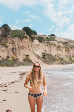Happy Young Woman with Long Blond Hair Standing on a Beach in her Bekini