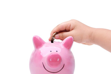 Hand of a young baby giving golden coin to a piggy bank / Young generation start saving for the future