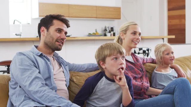 Family Sitting On Sofa In Lounge Watching Television Together