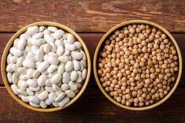 Assorted beans in bowls with chick-pea and kidney bean on wooden background.