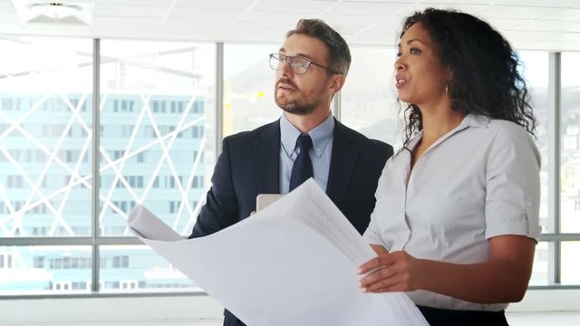 Businesspeople Meeting To Look At Plans In Empty Office