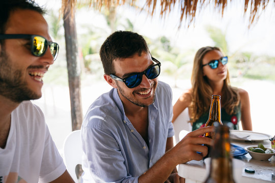 Friends having fun, laughing and enjoying a meal on a beach restaurant