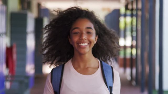 Black teenage girl walks into focus in high school corridor