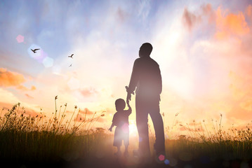 Happy Father's Day concept: Silhouette Father and son standing on meadow autumn sunrise background