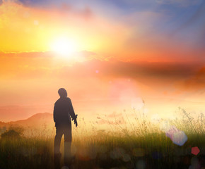 Silhouette of humble man standing to talking with God in mountain sunset background.