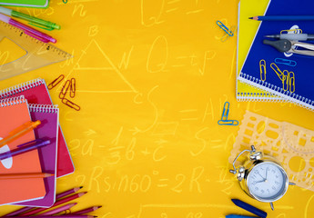back to school styed scene with school supplies on yellow with math formulas