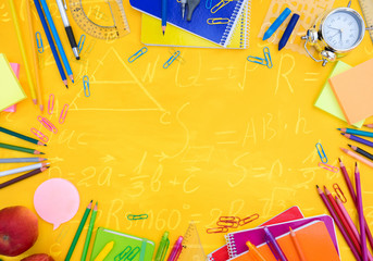 back to school or office styed scene with multicolored school supplies on yellow with math formulas