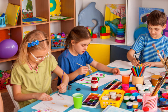 Small students girls painting in art school class. Children boy and girl drawing by paints on table. Children have fun at the children's club. Preparing for a school exhibition of plasticine.