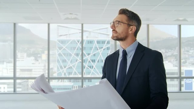 Male Architect In Modern Empty Office Looking At Plans