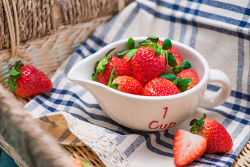 Bowl with fresh strawberry on blue wooden table.