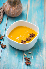 Pumpkin and carrot soup with cream and parsley on blue  wooden background.