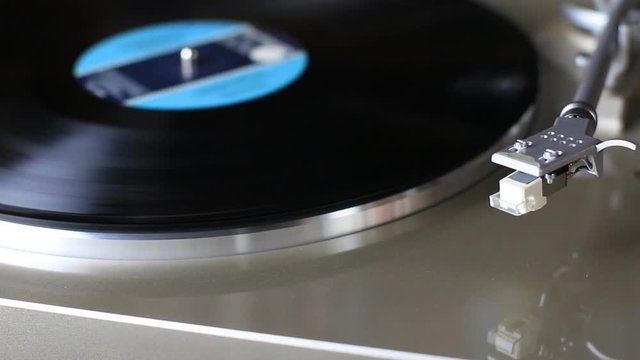 Silver colored vinyl player with automatic stylus playing a record