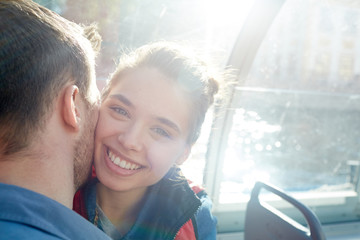 Laughing girl looking at camera with her boyfriend cheek by cheek