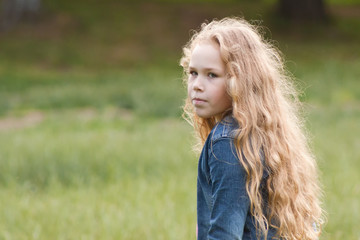 Fototapeta premium Little girl with curly hair feeling sadness - outdoor portrait
