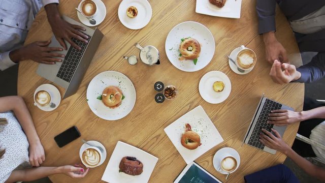 Overhead Shot Of Businesspeople Meeting Around Coffee Shop Table