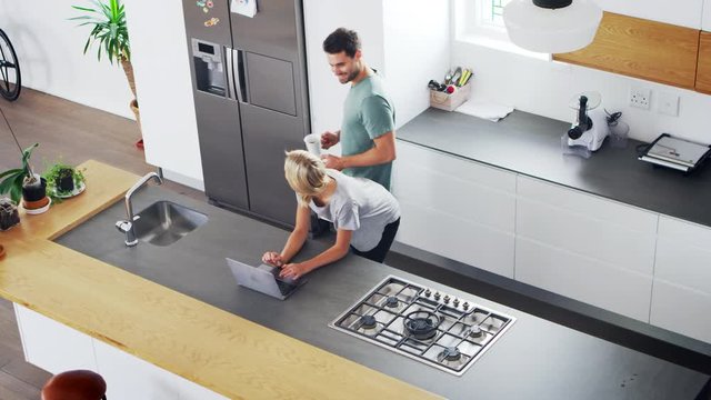Overhead View Of Couple Looking At Laptop In Modern Kitchen