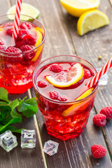 Summer drink with raspberries, lime and ice on a old wooden table