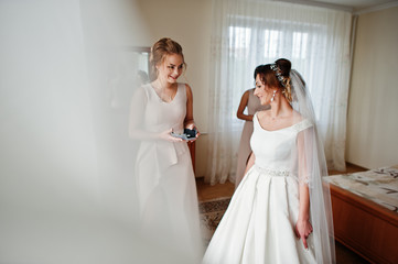 Naklejka premium Fabulous young bride posing with her bridesmiads in her room on the wedding day.