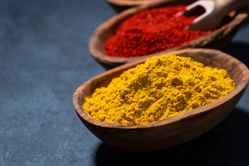 ground spicy paprika, turmeric and red pepper in a wooden bowl, closeup