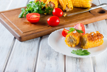 corn grilled with tomatoes and greens on a plate © vimart