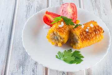 corn grilled with tomatoes and greens on a plate © vimart