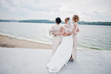 Stunning bride with pretty bridesmaids posing with bouquets on the lakeside.