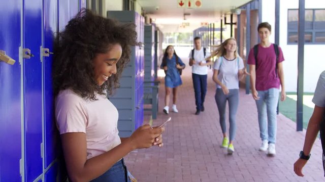 Black teenage girl using smartphone in school corridor