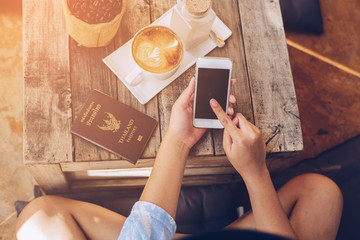 Close-up Of Woman Holding Mobile Phone In Front Of Coffee Cup